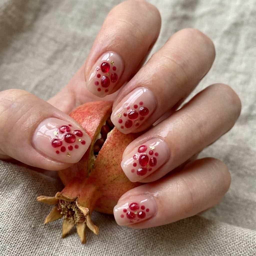 Deep red pomegranate summer fruit nails design with clustered arils